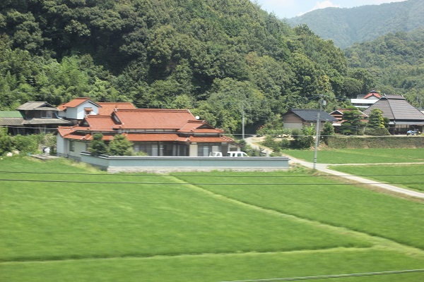 車窓、田んぼと赤い屋根の家の写真